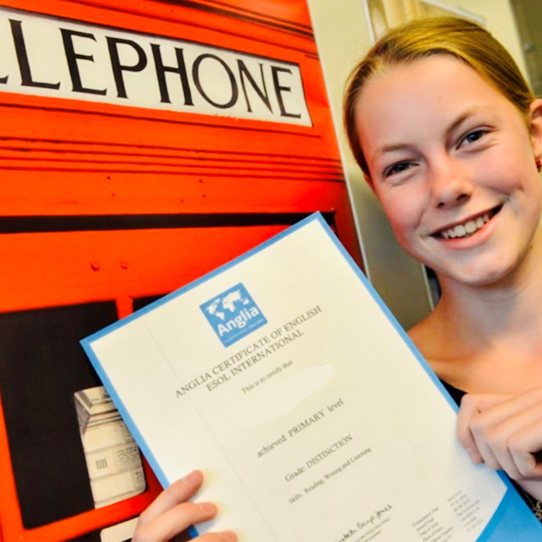 Meisje met Anglia certificaat bij rode telefooncel 